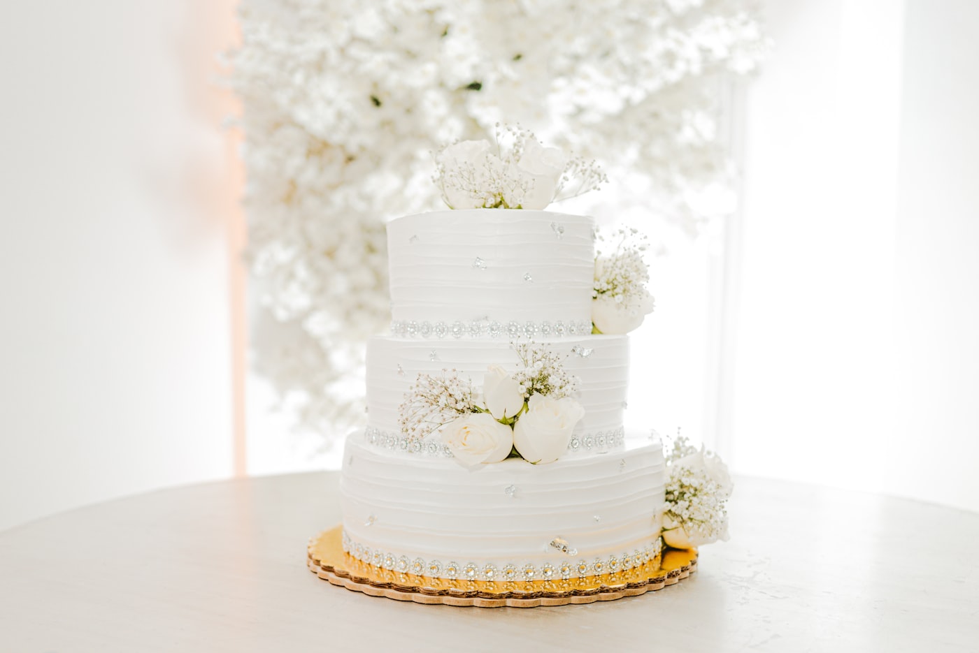 Three-tier white wedding cake with roses and silver detailing