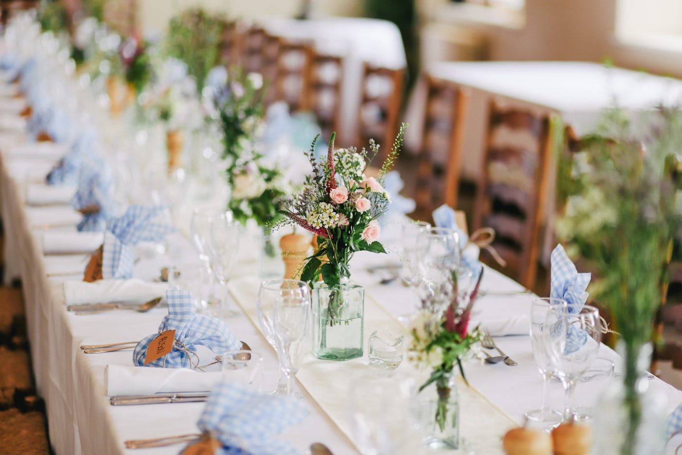 Soft pink floral arrangements along an elegantly set wedding reception table